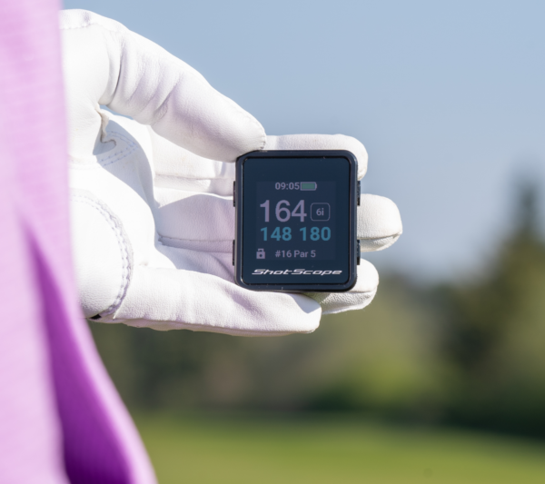 Female golfer holding H4 GPS handheld showing front, middle and back screen