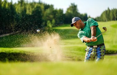 Male golfer plays from bunker