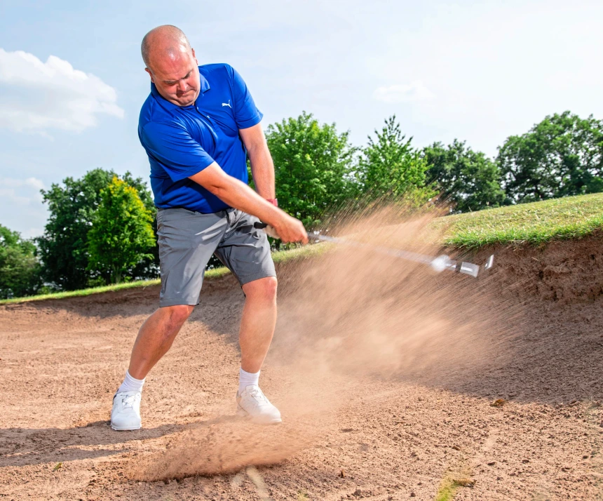 golfer hitting a golf shot out of the bunker