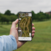 Male golfer holding mobile phone showing GPS hole view from Shot Scope app