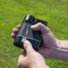 Male golfer holding Grey PRO LX+ rangefinder turning on slope switch