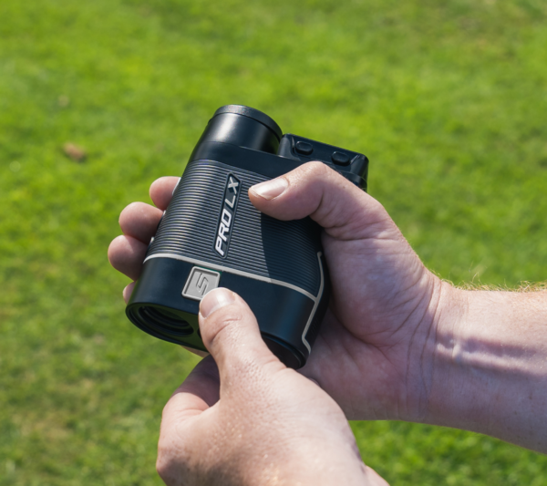 Male golfer holding Grey PRO LX+ rangefinder turning on slope switch